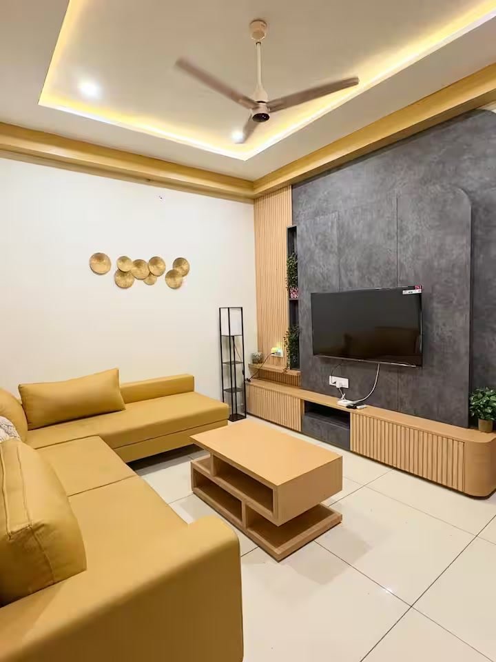 Living room — 5-seater sofa, smart TV with DTH, and pool view